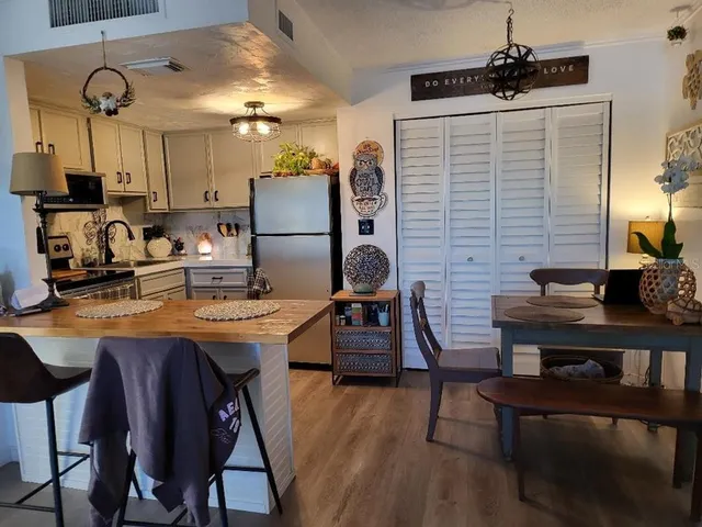 a kitchen with stainless steel appliances kitchen island a table chairs in it and wooden floors