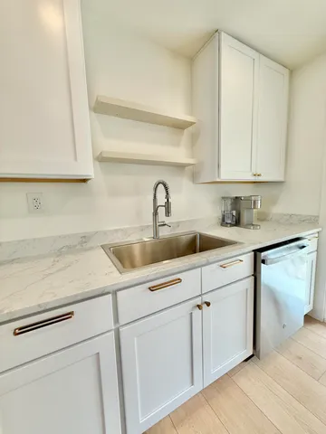a kitchen with white cabinets and sink
