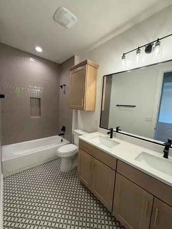 a bathroom with a double vanity sink toilet mirror and bathtub