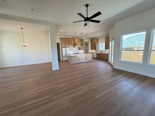 an empty room with wooden floor and ceiling fan