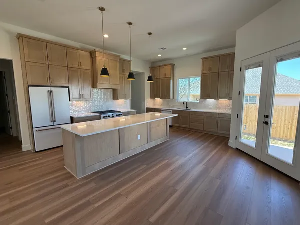 a large kitchen with stainless steel appliances a large counter top a sink a refrigerator and a window