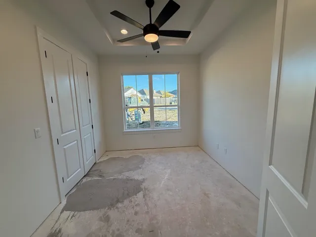 an empty room with windows and fan