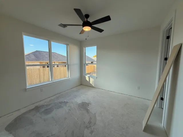 an empty room with windows and ceiling fan view