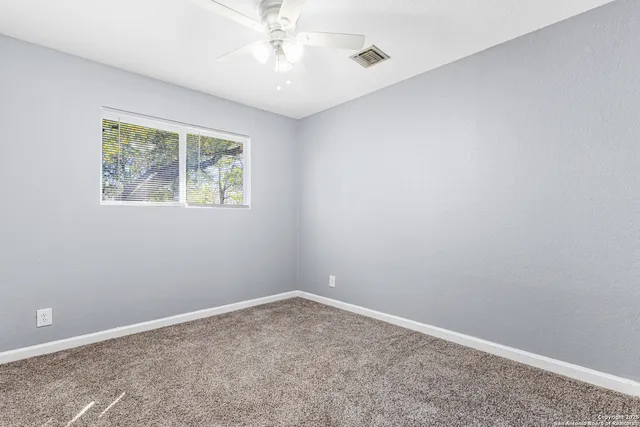 an empty room with a window and a chandelier fan