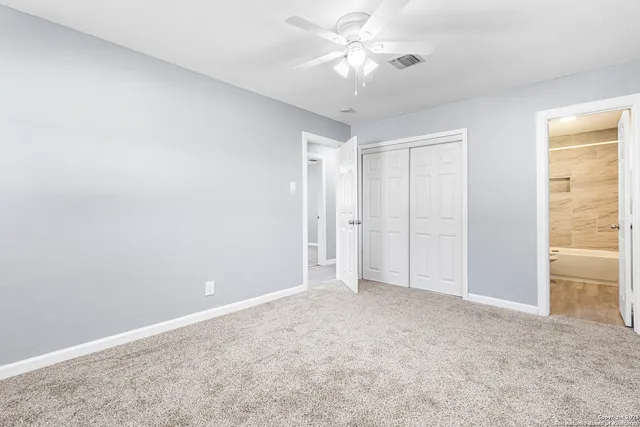 an empty room with a ceiling fan and a window