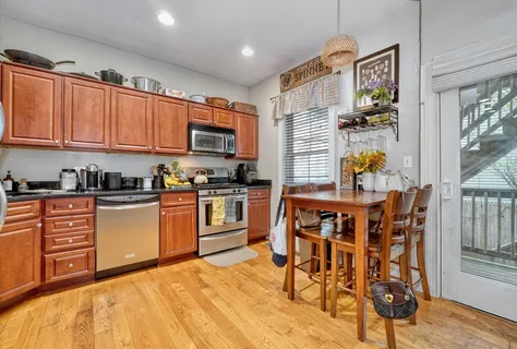 a kitchen with stainless steel appliances kitchen island granite countertop a refrigerator a stove a sink dishwasher and white cabinets with wooden floor