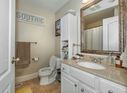 a bathroom with a granite countertop toilet a sink and a mirror