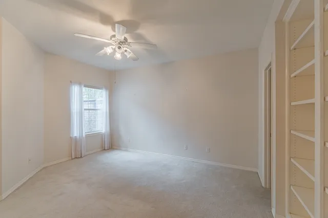 an empty room with a chandelier fan and windows