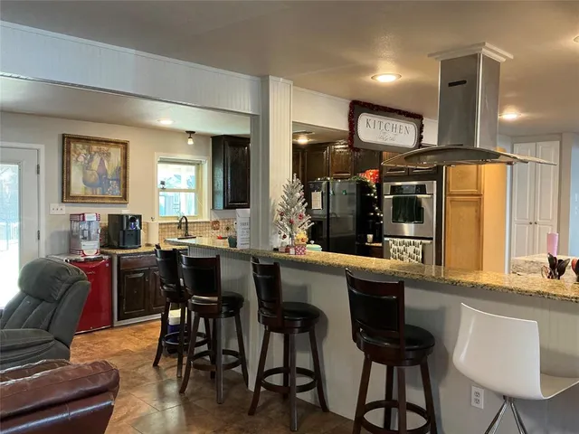 a kitchen with stainless steel appliances kitchen island granite countertop a table chairs and a refrigerator