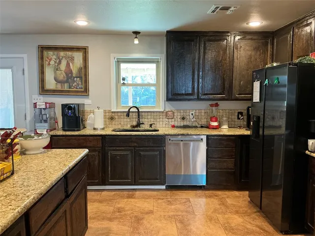 a kitchen with granite countertop kitchen island stainless steel appliances a refrigerator sink and cabinets