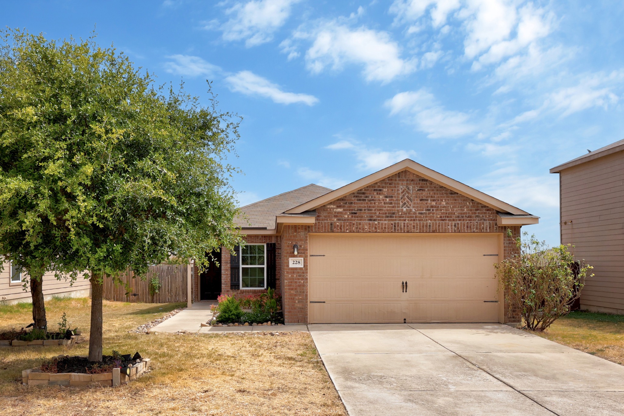 228 Millers Loop Jarrell, TX 76537 - Photo 3 of 26 A classic brick facade and a wide concrete driveway define this charming single-story home.