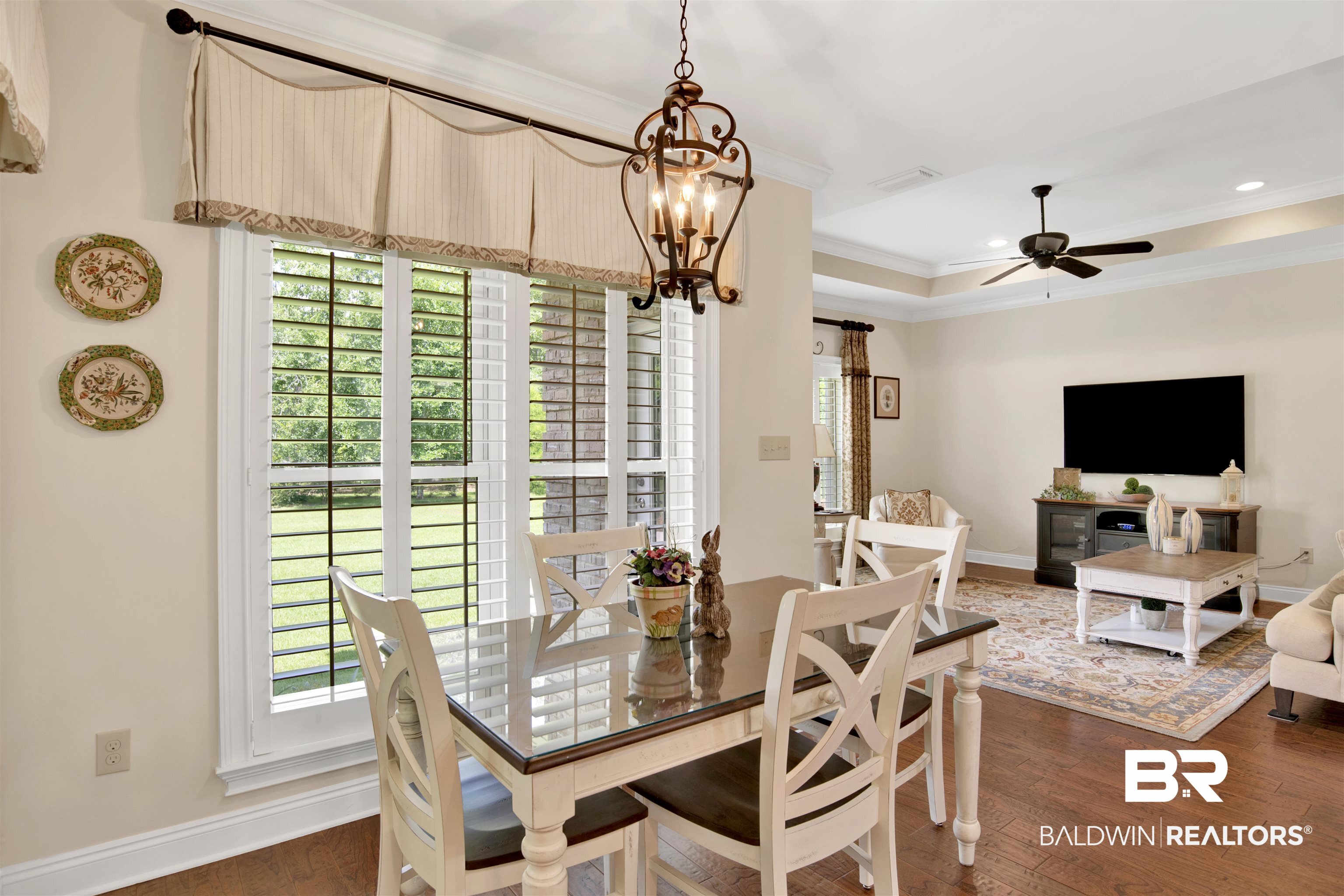 8358 Forest Lane Foley, AL 36535 - Photo 27 of 46 Dining room featuring crown molding, dark wood-type flooring, a chandelier, a ceiling fan, and a tray ceiling