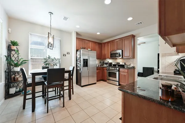 a kitchen with granite countertop a table chairs microwave and refrigerator
