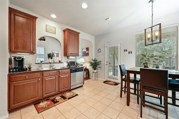 a kitchen with stainless steel appliances granite countertop a sink a stove a dining table and chairs