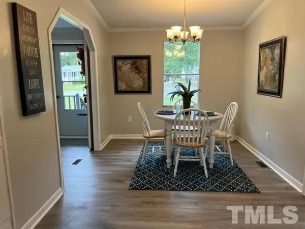 a dining room with wooden floor a chandelier a wooden table and chairs