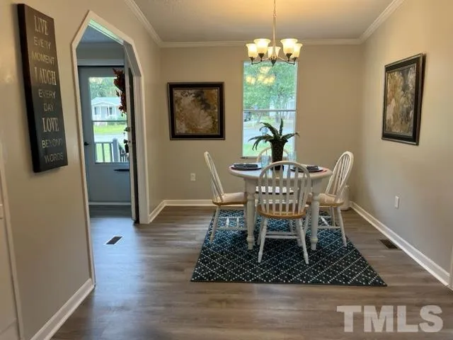 a dining room with wooden floor a chandelier a wooden table and chairs
