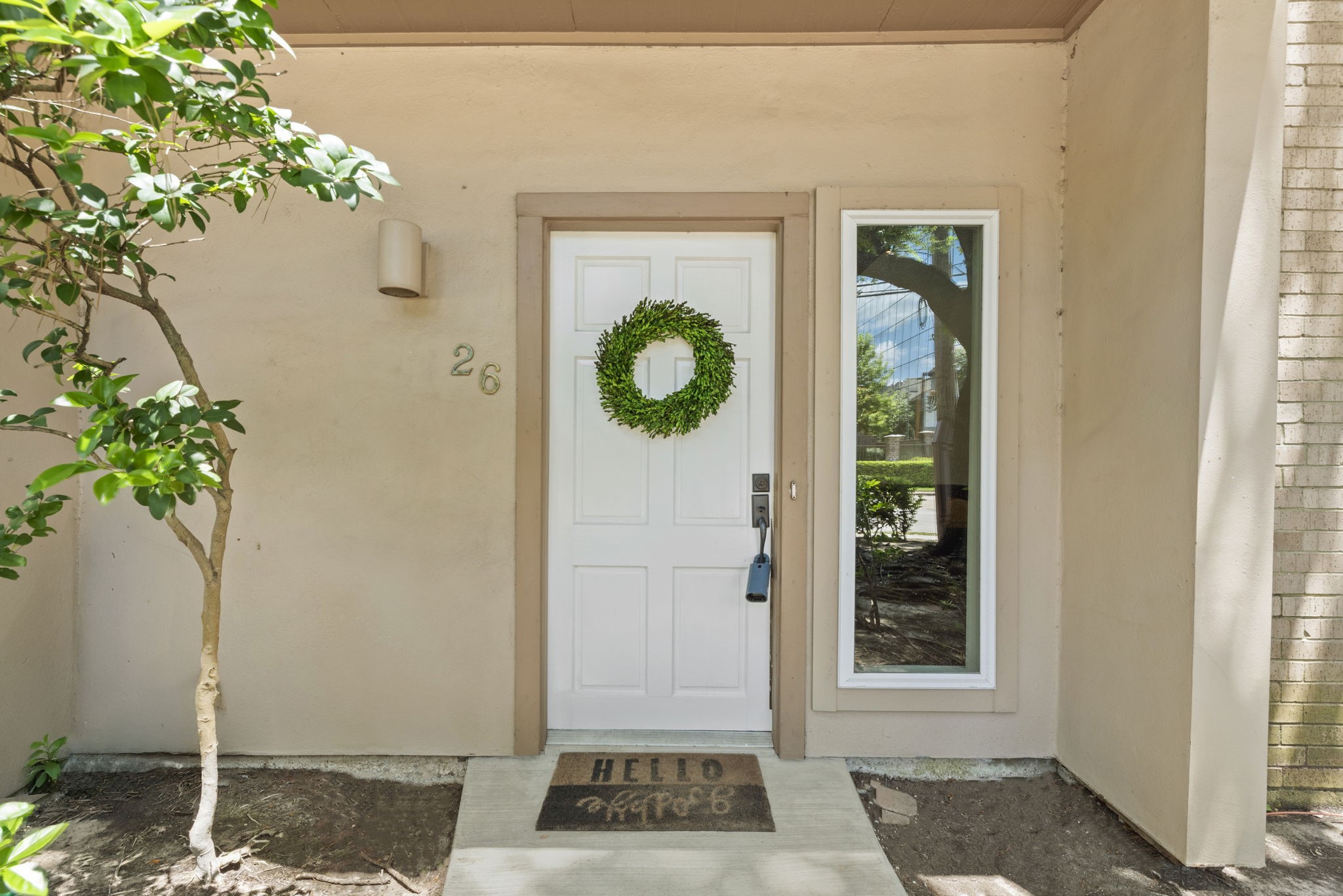 1115 Augusta Drive, Unit 26 Houston, TX 77057 - Photo 3 of 23 Charming front entrance with a welcoming wreath, tall window for natural light, and a cheerful “Hello there” doormat — setting the tone for a warm and stylish interior.