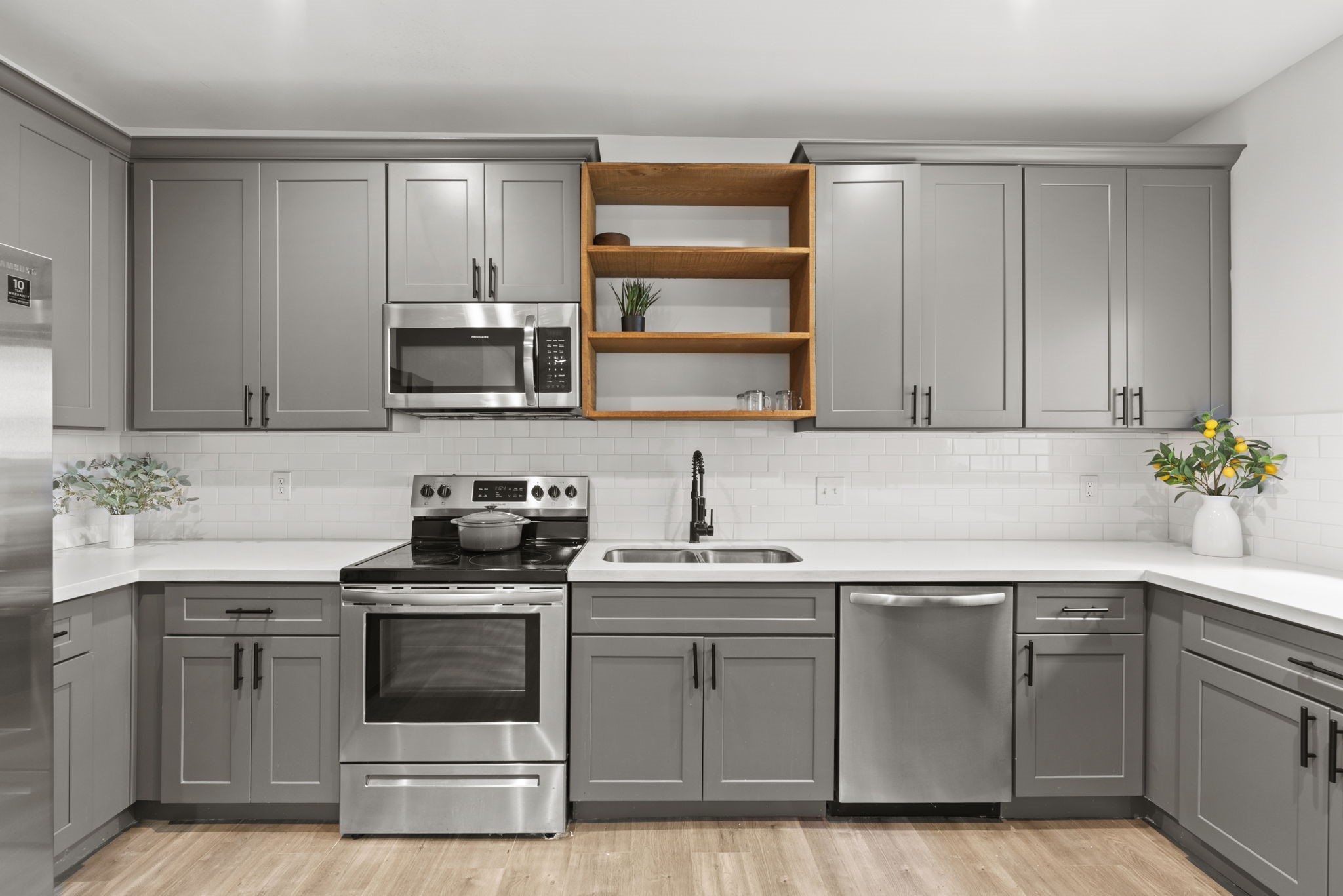 1115 Augusta Drive, Unit 26 Houston, TX 77057 - Photo 4 of 23 Contemporary kitchen with gray shaker cabinets, white countertops, subway tile backsplash, and open shelving — combining sleek design with everyday functionality.