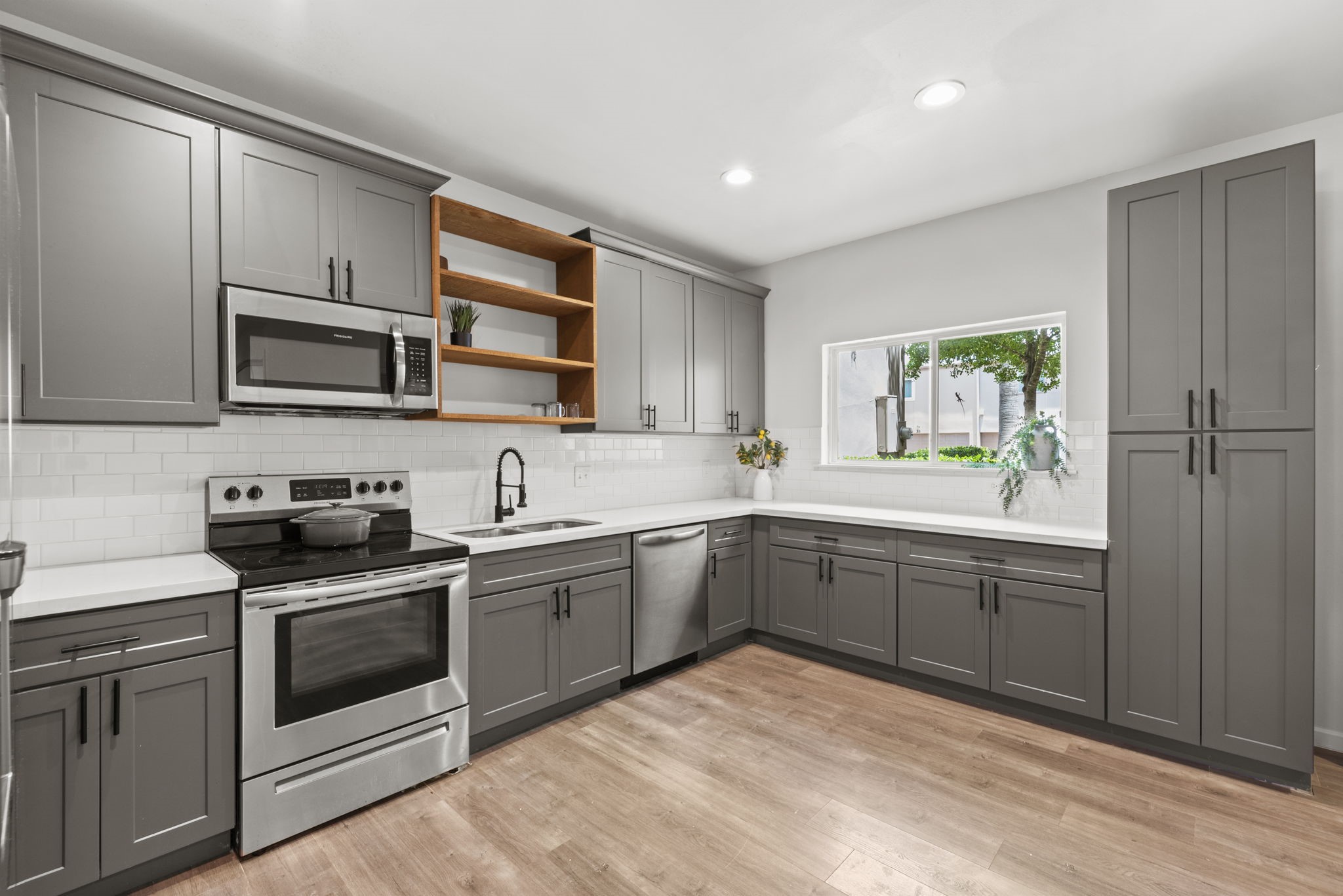 1115 Augusta Drive, Unit 26 Houston, TX 77057 - Photo 5 of 23 Contemporary U-shaped kitchen with gray shaker cabinets, quartz countertops, subway tile backsplash, and stainless steel appliances — designed for both style and efficiency.
