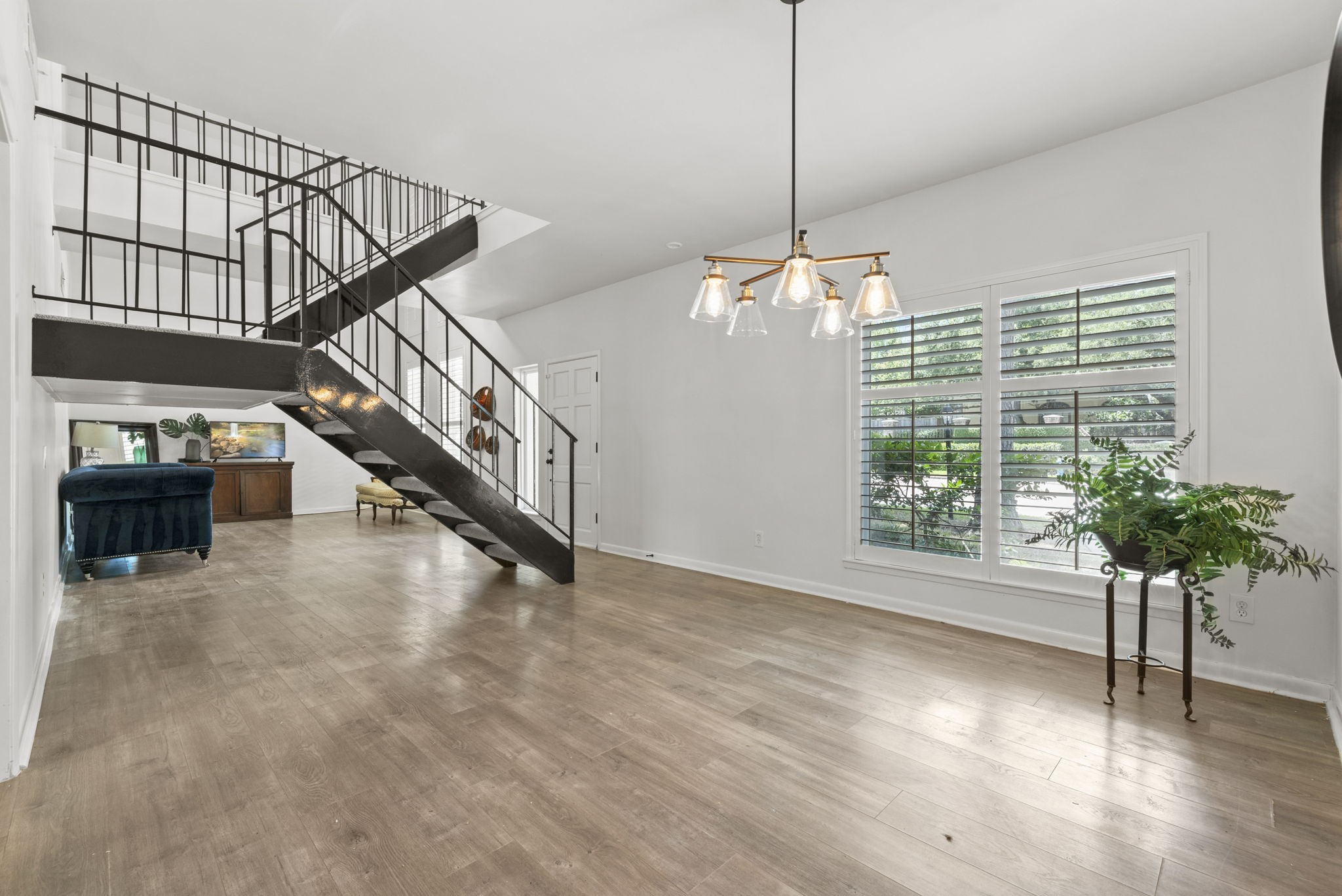 1115 Augusta Drive, Unit 26 Houston, TX 77057 - Photo 7 of 23 Modern open-concept living with light wood flooring, striking black metal staircase, and abundant natural light — a perfect blend of architectural interest and everyday comfort.