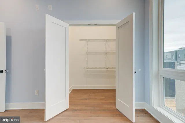 a view of an empty room with wooden floor and a window
