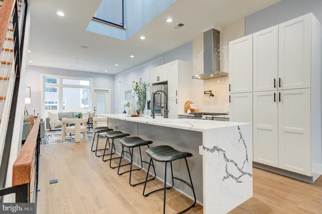 a kitchen with stainless steel appliances granite countertop a sink a stove a refrigerator and island with wooden floor