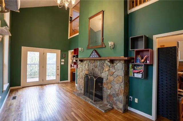 an empty room with wooden floor fireplace and windows