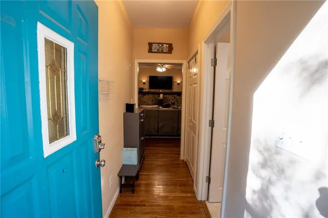 a view of a hallway with wooden floor and a bathroom
