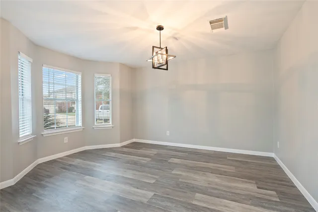 a view of an empty room with wooden floor and windows