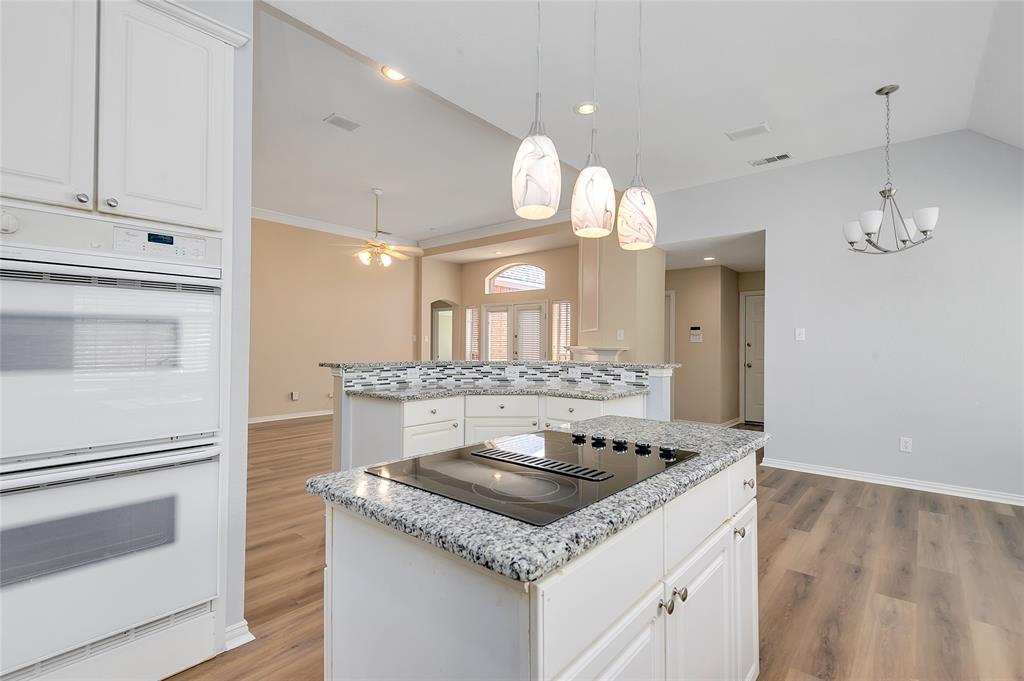 1404 Ranch Hill Drive Irving, TX 75063 - Photo 15 of 31 Kitchen featuring an integrated cooktop, granite countertops, white cabinetry, double wall ovens, and wood-finish flooring
