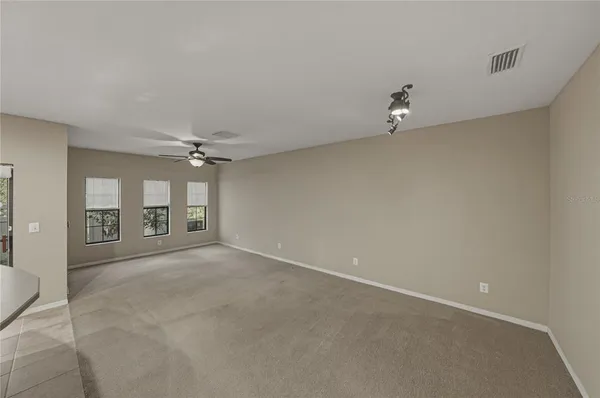 an empty room with a ceiling fan and windows
