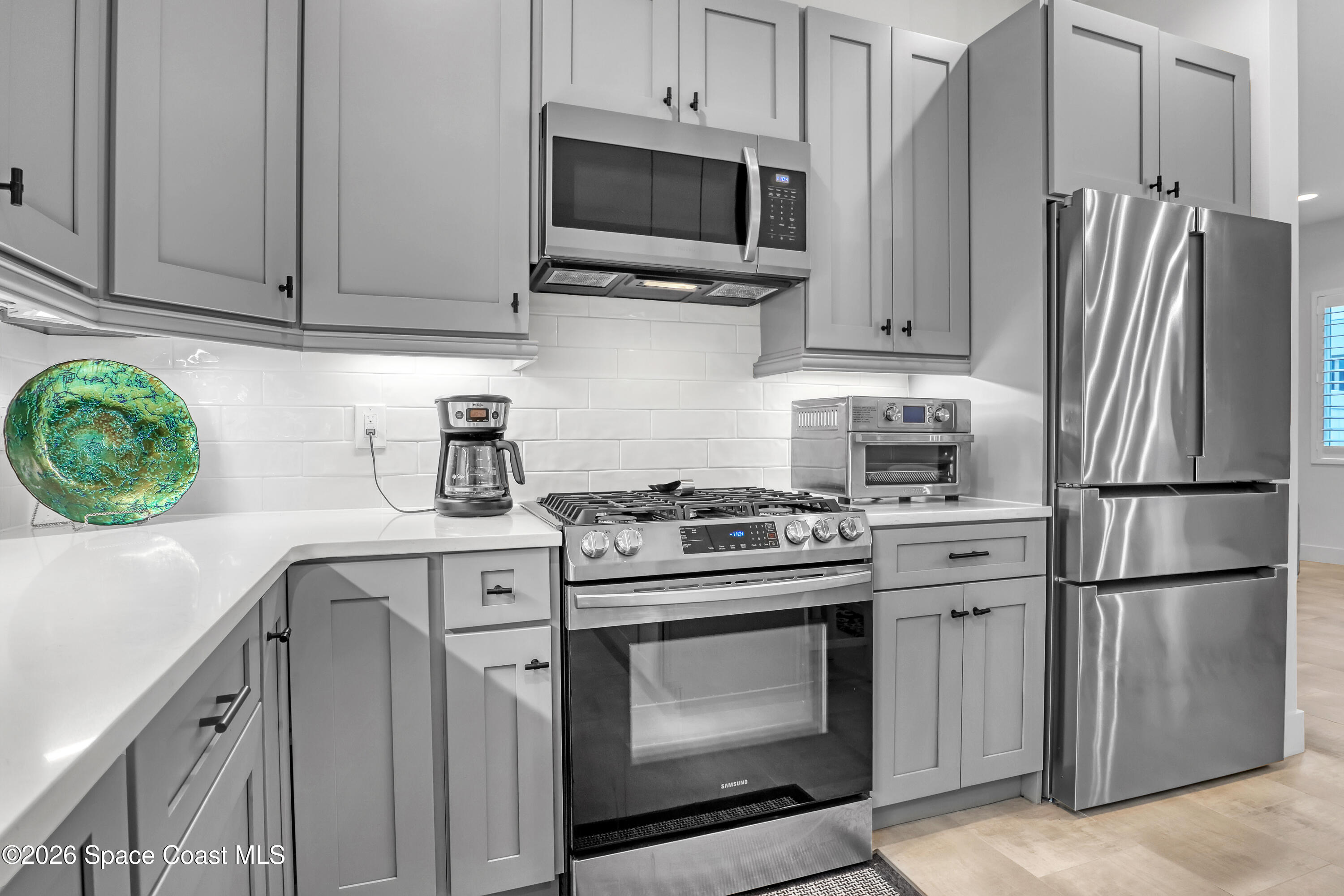 2188 Country Club Road Melbourne, FL 32901 - Photo 15 of 57 a kitchen with stainless steel appliances white cabinets and a stove top oven
