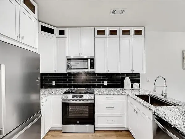 a kitchen with stainless steel appliances kitchen island granite countertop a sink and cabinets