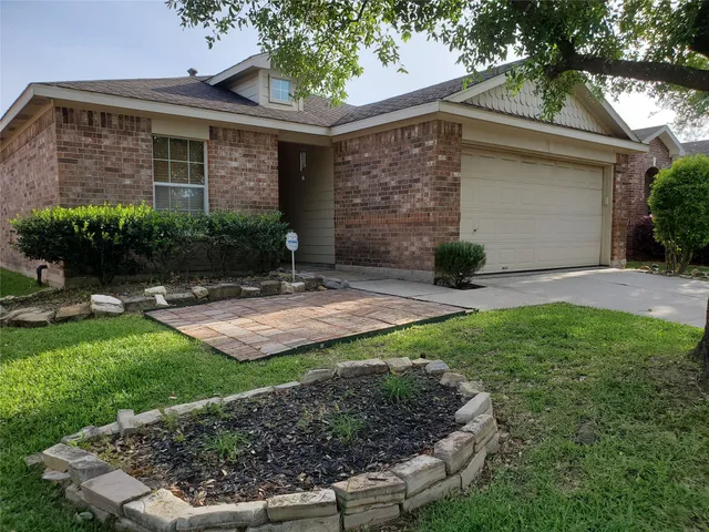 a view of a brick house with a yard and a large tree