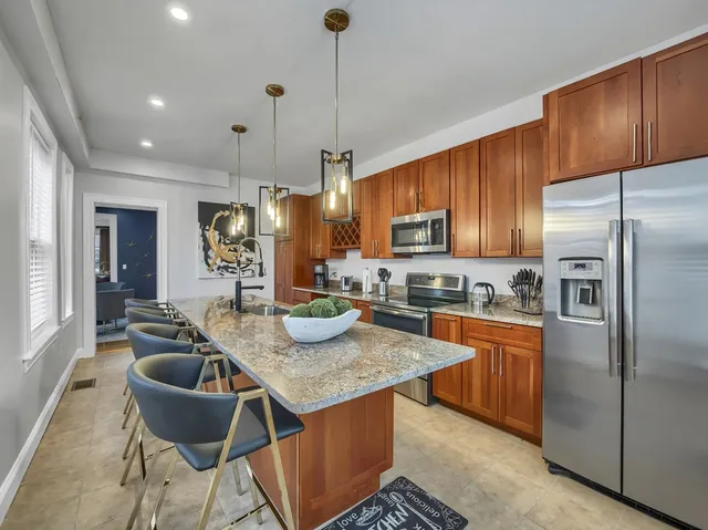 a kitchen with granite countertop a table chairs microwave and refrigerator