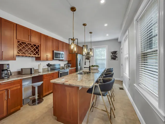 a kitchen with stainless steel appliances granite countertop a sink a stove a refrigerator and island