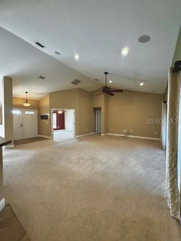 en empty room with windows and chandelier fan