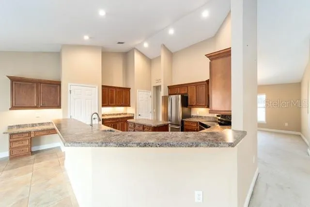 a large kitchen with stainless steel appliances granite countertop a sink stove refrigerator granite counter tops and a window