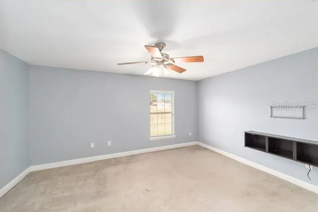 an empty room with a chandelier fan and windows