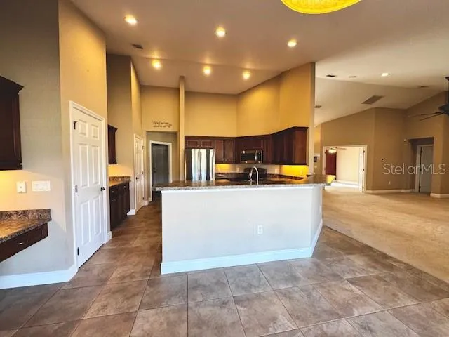 a large kitchen with stainless steel appliances kitchen island a large counter top and a view of living room
