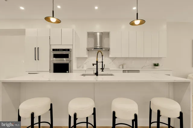 a kitchen with stainless steel appliances a stove a sink island and a refrigerator with wooden floor