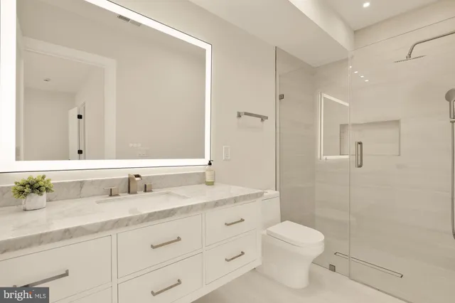 a bathroom with a shower sink vanity mirror and toilet