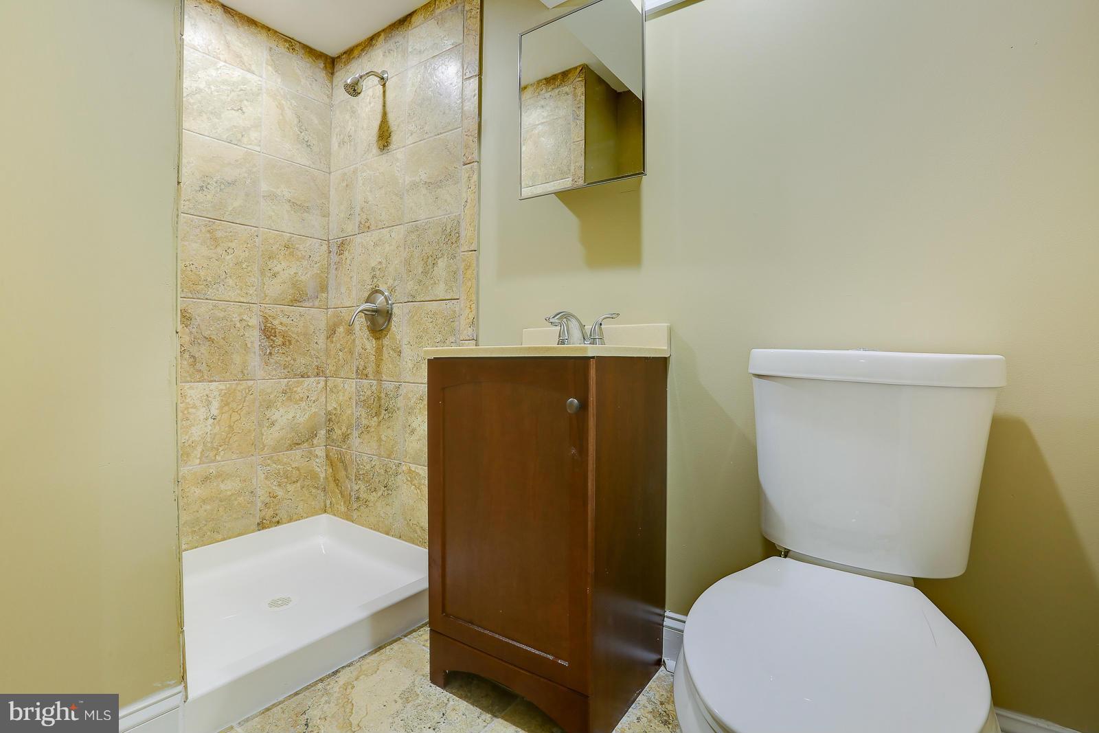 3216 Mayfair Road Baltimore, MD 21207 - Photo 20 of 24 a white toilet sitting next to a bathroom sink and a shower
