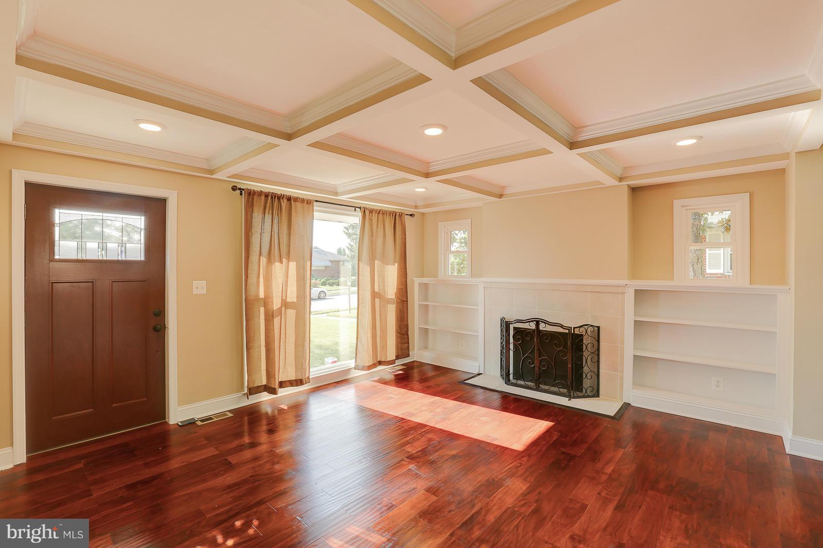 3216 Mayfair Road Baltimore, MD 21207 - Photo 3 of 24 an empty room with wooden floor fireplace and windows