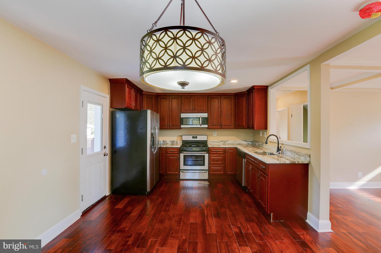 3216 Mayfair Road Baltimore, MD 21207 - Photo 7 of 24 a kitchen with stainless steel appliances granite countertop a refrigerator a stove and a wooden floors