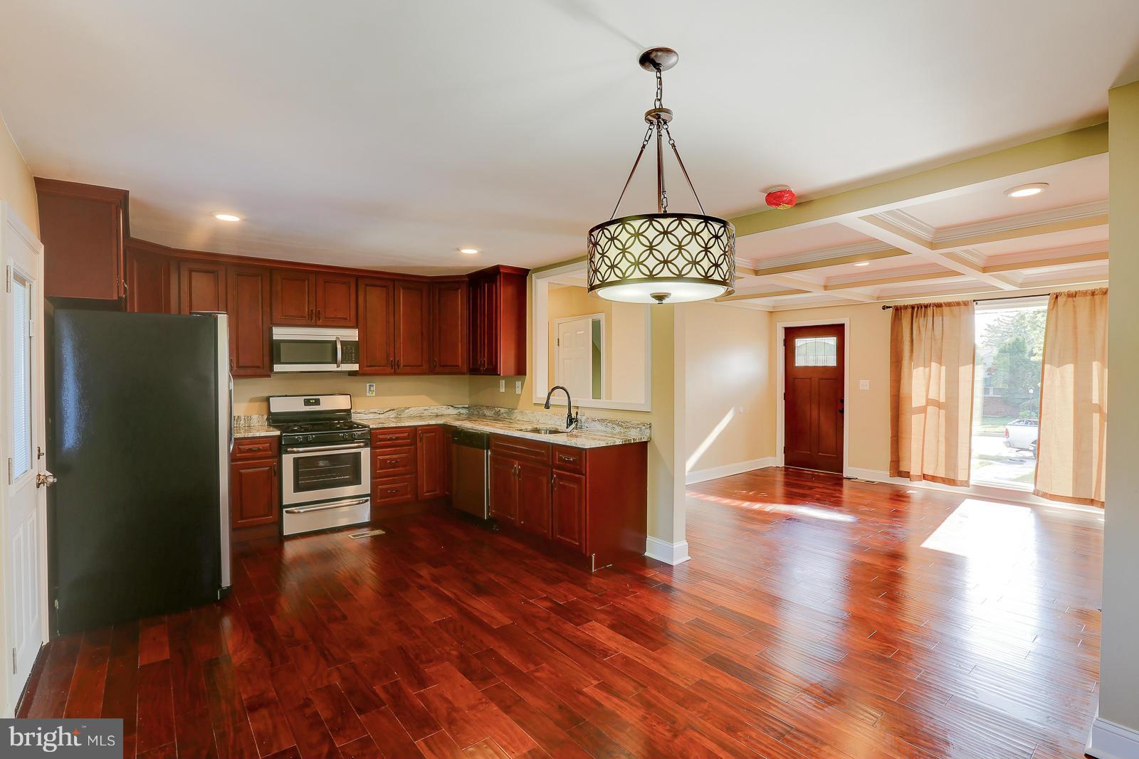3216 Mayfair Road Baltimore, MD 21207 - Photo 8 of 24 a large kitchen with a chandelier stainless steel appliances and wooden floor