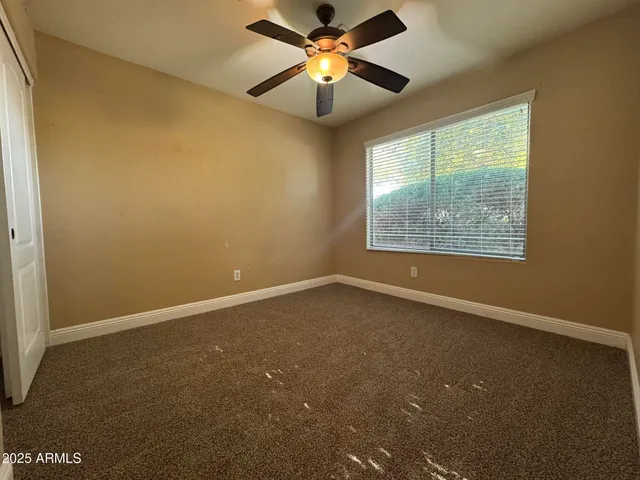 a view of an empty room with window and chandelier fan