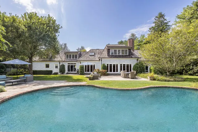 a view of a swimming pool with lawn chairs under an umbrella