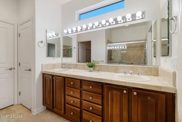 a bathroom with a granite countertop shower a sink and a mirror