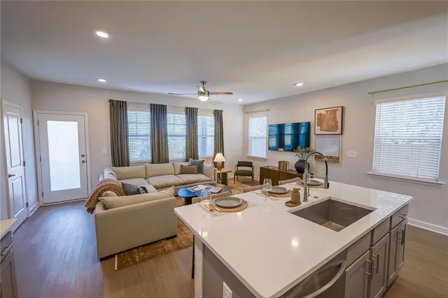a living room with furniture kitchen view and a large window